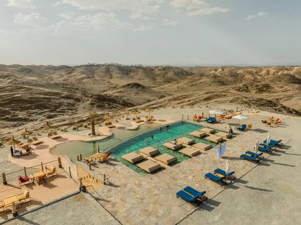 A stunning Agafay desert luxury camp with private pool overlooking the Atlas Mountains at sunset