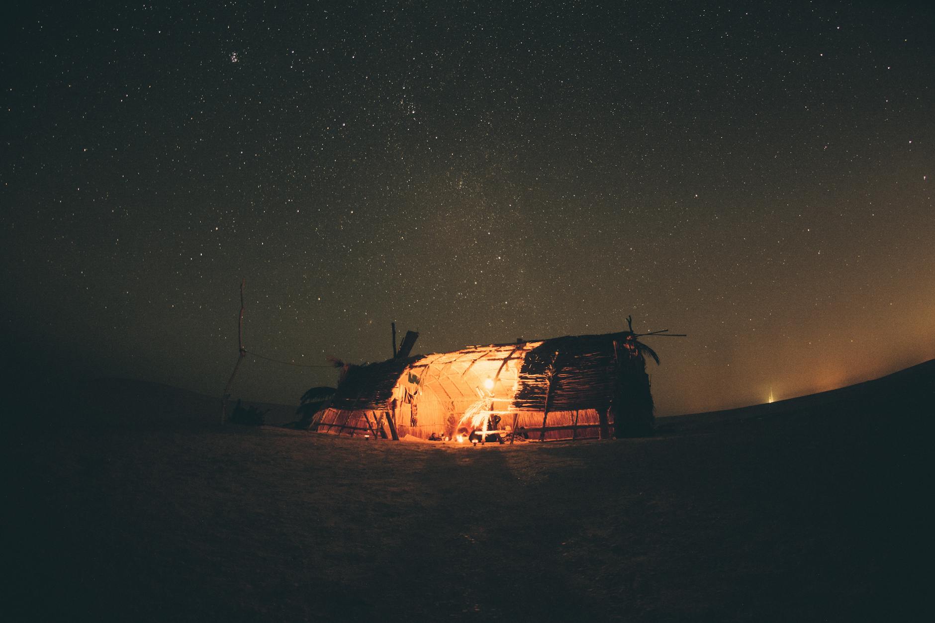 A stunning sunset view over the best luxury camp in agafay desert with glowing lanterns and luxury tents