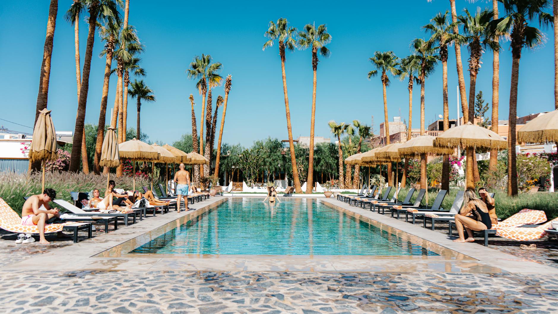 A luxury desert camp in Morocco featuring a private pool overlooking the golden hills under a clear blue sky during a premium marrakech desert tour with private pool.