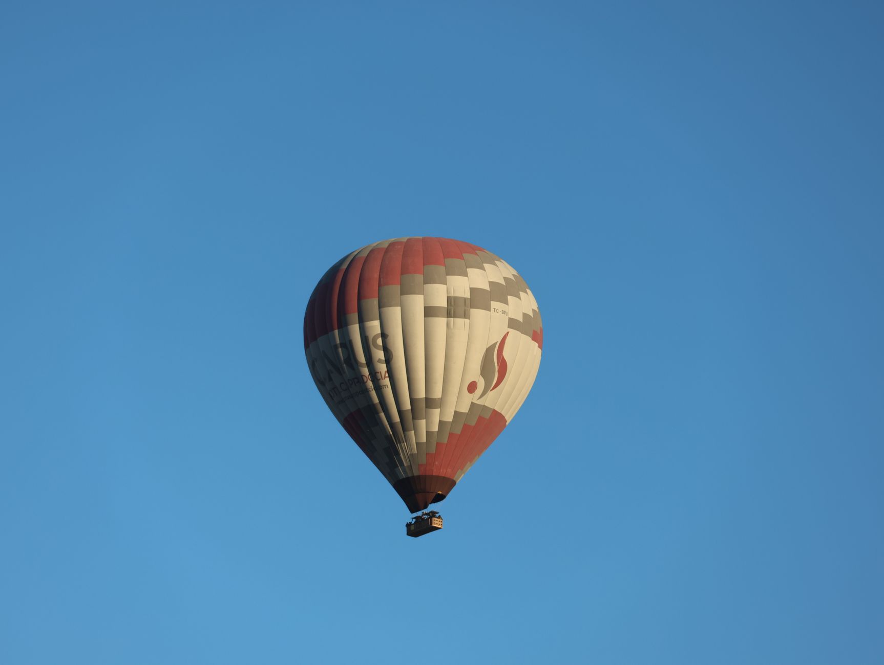 hot air balloon marrakech price - A colorful hot air balloon rising over the plains near Marrakech at sunrise with the Atlas Mountains in the background.